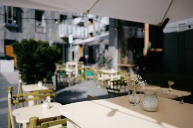 Süslü Mavi Saksıda Sarı Çiçeklerle Yuvarlak Masa Üzerinde Büyüleyici Açık Cafe Sahnesi