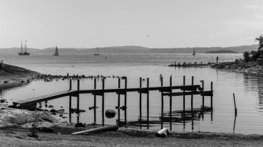 Serene Black ve White Lakeside Sailboat ve Tahta İskeleli Sakin Su Yansıması