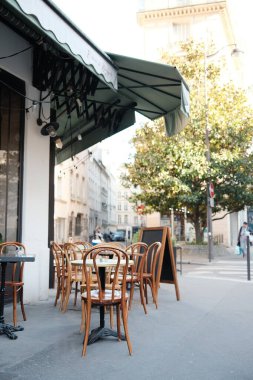 Güneşli Şehir Caddesinde Tahta Sandalyeler ve Masalarla Büyüleyici Açık Cafe Ayarları