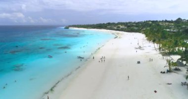 Mavi okyanus manzarası, kumlu sahil, yazın güneşli bir günde yüzen insanlar, kayıklar ve yatlar. Dron 'un deniz manzarası, beyaz kum, palmiye ağaçları. Tropikal. Zanzibar, Afrika