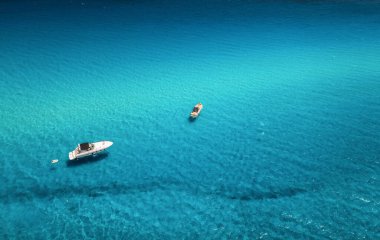 Yazın günbatımında mavi denizde güzel lüks yat ve tekne manzarası. Sardunya adası, İtalya. Sürat teknesinin üst görüntüsü, deniz kıyısı, masmavi berrak su. Seyahat et. Tropik bir manzara. Yat.