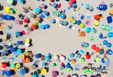 Kumlu sahildeki renkli şemsiyelerin havadan görünüşü, yazın günbatımında insanlar İtalya, Sardunya 'da. Tropik bir manzara. Seyahat ve tatil. İHA 'nın yukarıdan aşağıya bakışı. Kavram. Metin için arkaplan