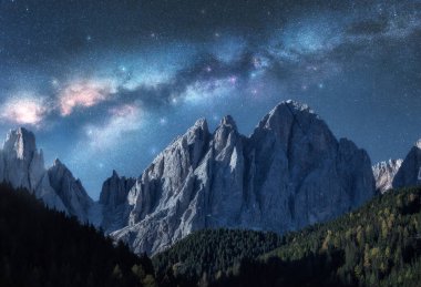 Dolomites, İtalya 'da yaz aylarında yıldızlı bir gecede Samanyolu' nun üzerindeki güzel kayalıklar. Yıldızlı mavi gökyüzü ve yüksek dağlı kayalık dağların ve ağaçların üzerindeki parlak Samanyolu manzarası. Uzay arkaplanı. Doğa
