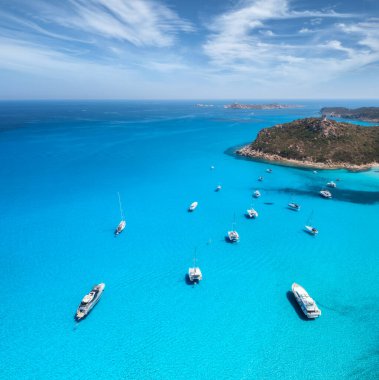 Yazın güneşli bir günde mavi denizde lüks yatların hava manzarası. Sardunya, İtalya. Sürat tekneleri, yatlar, deniz lagünü, sahil, şeffaf su, gökyüzü. İHA 'nın üst görüntüsü. Tropik deniz manzarası