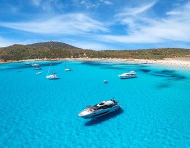 Aerial view of luxury yachts on blue sea at sunny day in summer. Sardinia, Italy. View from above of speed boats, yachts, sea bay, sandy beach, clear water, sky. Top view from drone. Tropical seascape