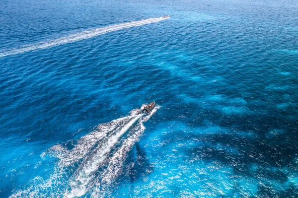 Aerial view of beautiful floating speed boat in blue sea at sunny day in summer. Sardinia island, Italy. Top view of yacht, turquoise transparent water. Travel. Tropical seascape. Motorboat