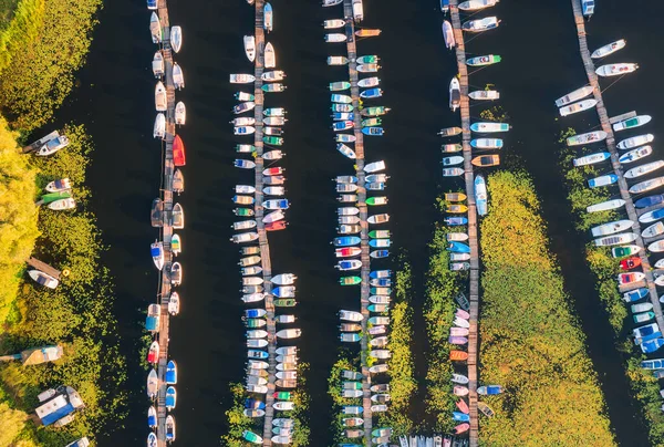 Aerial view of boats and luxury yachts in dock at sunset in summer. Colorful landscape with sailboats and motorboats in river bay, jetty, water. Top view from drone of harbor. Transport