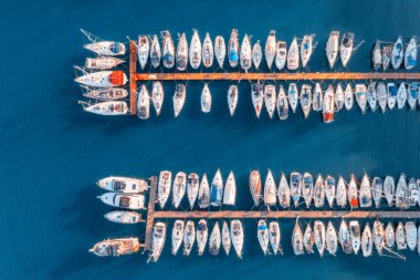 Aerial view of boats and luxure yachts in dock at sunset in summer in Pula, Croatia. Colorful landscape with sailboats and motorboats in sea bay, jatty, clear blue sea. Drone view of harbor. Travel