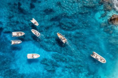 Aerial view of small motorboats in blue sea at sunny bright day in summer. Sardinia island, Italy. Drone view of speed boats, yacths, rocky sea coast, transparent water. Travel. Beautiful seascape