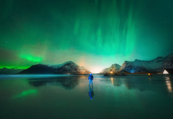 北のライトと夜のビーチで男 ノルウェーのロフテン島 美しいオーロラのボアリス 極灯だ オーロラ 水の反射 山と冬の風景 — ストック写真