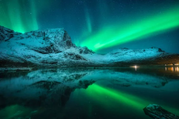 北方的灯光照射在雪山之上 海面上 夜间在挪威罗浮敦的水面上反射 北极光和积雪覆盖了岩石 有极光的冬季风景 有星星和峡湾的天空 — 图库照片