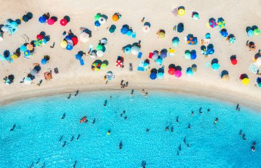 Kumlu sahildeki renkli şemsiyelerin havadan görünüşü, güneşli yaz günlerinde mavi denizdeki insanlar. Tuerredda Sahili, Sardunya, İtalya. Turkuaz suyu olan tropik bir manzara. Seyahat ve tatil. Üst İHA görünümü