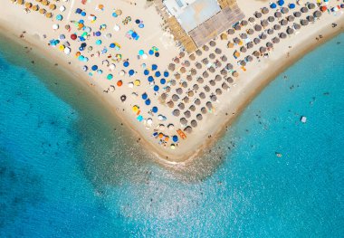 Aerial view of colorful umbrellas on sandy beach, people in blue sea at summer sunny day. Tuerredda Beach, Sardinia, Italy. Tropical landscape with turquoise water. Travel and vacation. Top drone view clipart