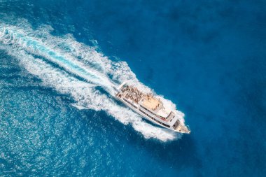 Aerial view of beautiful floating yacht in blue sea at sunny day in summer. Sardinia island, Italy. Drone view of speed boat, sea coast, transparent water. Travel. Tropical landscape. Yachting
