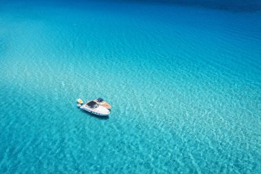 Yazın güneşli bir günde mavi denizde güzel bir yat ve tekne manzarası. Sardunya adası, İtalya. Sürat teknesinin, okyanusun, masmavi berrak suyun üst drone görüntüsü. Seyahat et. Tropik bir manzara. Yat.