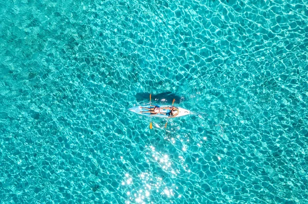 夏の晴れた日には青い海の人々とカヤックの空中ビュー 澄んだ紺碧の水の中に浮かぶカヌーの上の男と女 イタリアのサルデーニャ島 熱帯の風景 ボードだ アクティブな旅行 トップ表示 — ストック写真