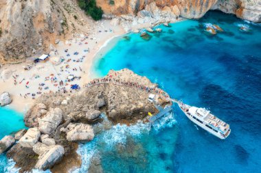 Güneşli yaz gününde insanlarla dolu yatın ve kumlu plajın havadan görünüşü. Kayalık deniz kıyısındaki İHA 'nın üst görüntüsü. Akdeniz 'de. İtalya 'nın Sardunya adasında seyahat et. Tropikal manzara
