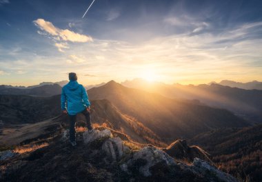 Tepedeki taş üstüne taş adam ve sonbaharda renkli günbatımında sisli güzel dağ vadisi. Dolomitler, İtalya. Guy, sisli dağ sırtları, turuncu çimenler ve ağaçlar, sonbaharda güneşli mavi gökyüzü. Yürüyüş