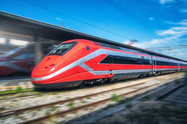 Tren istasyonunda kırmızı hızlı tren hareket ediyor. Hızlı hareket eden modern şehirlerarası tren ve bulanık arka plan. Demiryolu platformu. İtalya 'da demiryolu. Ticari ve yolcu taşımacılığı