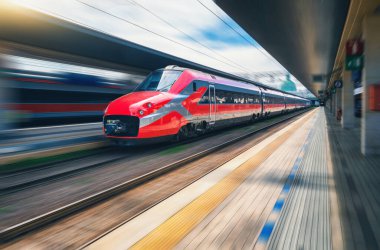 Tren istasyonunda kırmızı hızlı tren hareket ediyor. Hızlı hareket eden modern şehirlerarası tren ve bulanık arka plan. Demiryolu platformu. İtalya 'da demiryolu. Ticari ve yolcu taşımacılığı