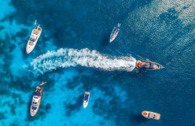 Yazın güneşli bir günde mavi denizde lüks yatların ve teknelerin hava manzarası. Sardunya, İtalya 'ya seyahat. Sürat tekneleri, yatlar, deniz koyları, kayalık kıyılar, şeffaf gök mavisi suyu. Deniz Burnu