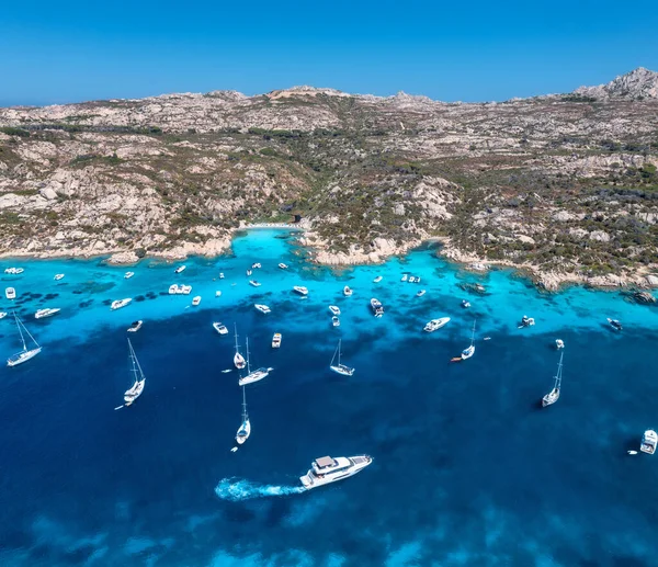 stock image Aerial view of luxury yachts and boats on blue sea at summer sunny day. Travel in Sardinia, Italy. Drone view from above of speed boats, yachts, sea bay, rocky coast, transparent water. Seascape