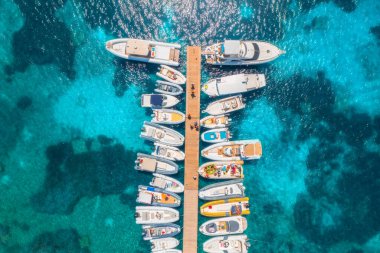 Aerial view of boats and luxure yachts in dock at sunset in summer in Sardinia, Italy. Colorful landscape with sailboats and motorboats in sea bay, jatty, clear blue sea. Top view of harbor. Travel
