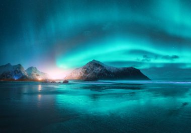 Kışın yıldızlı gecelerde Kuzey Işıkları ve plaj. Lofoten Adaları, Norveç. Güzel Aurora borealis. Kutup ışıklarıyla gökyüzü. Aurora ile manzara, su ile gökyüzü yansıması ile deniz, dağlar
