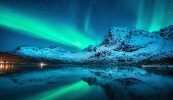 北方的灯光照射在雪山之上 海面上 反映在挪威罗浮敦冬夜的水面上 北极光和积雪覆盖了岩石 有极光的风景 有星星和峡湾的天空 — 图库照片