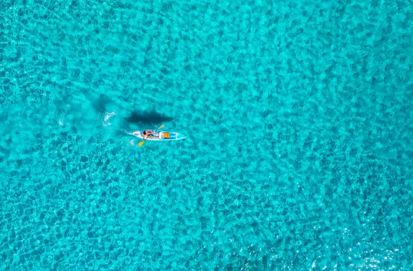 夏の晴れた日に青い海のカヤックの空中ビュー 透明紺碧の水で海に浮かぶカヌーの上の男 イタリアのサルデーニャ島 熱帯の海 ボードだ アクティブな旅行 トップドローンビュー — ストック写真