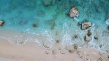 Açık mavi denizin havadan görünüşü, suda taşlar ve kayalar, gün batımında boş plaj. İtalya, Sardunya adasında yaz mevsimi. Gök mavisi suyu olan tropik deniz manzarası. Deniz kıyısının en üst hava aracı görüntüsü. Doğa. Seyahat