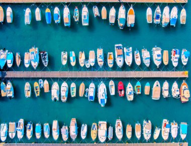 Hırvatistan 'ın Krk adasında yaz günü gün batımında rıhtımda bulunan tekne ve lüks yatların hava manzarası. Deniz koyunda yelkenli ve motorlu teknelerle dolu renkli bir manzara. İskele, açık mavi deniz. Limanın üst görünümü