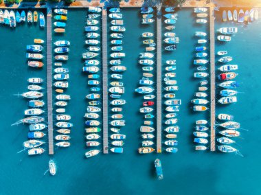 Hırvatistan 'ın Krk adasında yaz günü gün batımında rıhtımda bulunan tekne ve lüks yatların hava manzarası. Deniz koyunda yelkenli ve motorlu teknelerle dolu renkli bir manzara. İskele, açık mavi deniz. Limanın üst görünümü