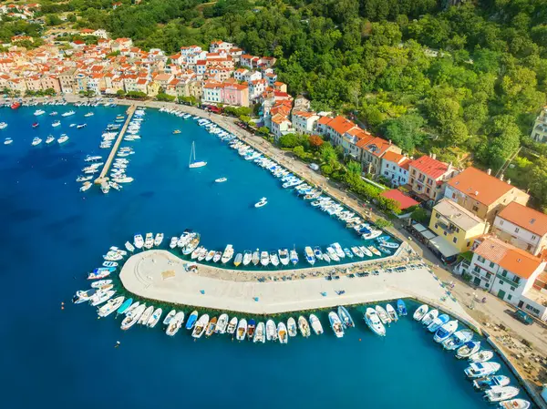 Aerial view of boats and luxure yachts, buildings at summer sunrise. Beautiful city Baska, Krk island, Croatia. Colorful landscape with sailboats and motorboats, architecture, sea bay, jatty. Top view