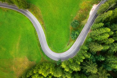Yazın günbatımında yeşil çayırlardaki yol ve ağaçların havadan görünüşü. Kırsal yolun en iyi drone manzarası, baharda orman. Yol manzarası, orman, Dolomitler, İtalya 'da çimler. Ulaşım