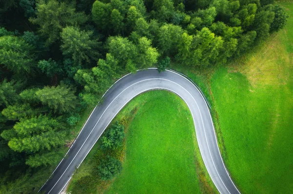 Yazın günbatımında yeşil çayırlardaki yol ve ağaçların havadan görünüşü. Kırsal yolun en iyi drone manzarası, baharda orman. Yol manzarası, orman, Dolomitler, İtalya 'da çimler. Ulaşım