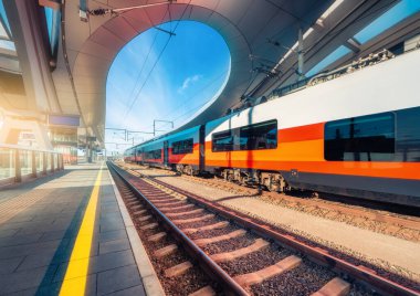 Graz, Avusturya 'da günbatımında modern tren istasyonunda yüksek hızlı tren. Kapalı tren peronunda güzel turuncu şehirlerarası yolcu treni. Demiryolu. Yolcu demiryolu taşımacılığı