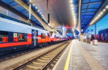 Avusturya 'nın Graz kentindeki modern tren istasyonunda yüksek hızlı tren. Güzel turuncu şehirlerarası yolcu treni kapalı tren peronunda ışıklarla. Demiryolu. Demiryolu taşımacılığı