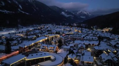 Slovenya 'nın Kranjska Gora köyündeki güzel kayak merkezinin soğuk kış gecelerinde hava manzarası. Kardaki binaların, sokak ışıklarının, yolların, karlı dağların, alacakaranlıktaki gökyüzünün en yüksek insansız hava aracı görüntüsü. Triglav Parkı