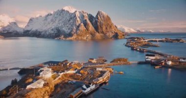 Karlı kayaların havadan görünüşü, deniz, köprü, dağ, yol, kışın alçak bulutlu adalar. Norveç, Lofoten Adaları 'ndaki Reine ve Hamnoy köylerinin güzel insansız hava aracı manzarası