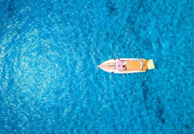Yazın güneşli bir günde mavi denizde güzel lüks bir yatın havadan görünüşü. Sardunya, İtalya. Sürat teknesi, deniz kıyısı, şeffaf gök mavisi. Seyahat et. Tropik bir manzara. Yatçılık. Deniz Burnu