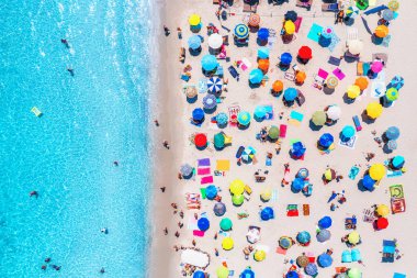 Kumlu sahildeki renkli şemsiyelerin havadan görünüşü, İtalya 'nın Sardunya şehrinde yaz güneşli bir günde mavi denizde yüzen insanlar. Berrak gök mavisi suyu olan tropik bir yer. Seyahat ve tatil. Üst İHA görünümü