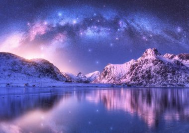 Samanyolu kemeri, deniz kıyıları ve kış geceleri karla kaplı dağlar. Lofoten Adaları, Norveç. Arktik manzara, yıldızlı mor gökyüzü, kavisli samanyolu suya, karlı kayalara yansıyor. Boşluk