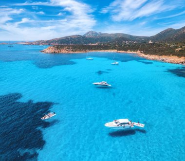 Yazın güneşli bir günde mavi denizde lüks yatların hava manzarası. Sardunya, İtalya. Sürat tekneleri, yatlar, deniz lagünü, sahil, şeffaf su, gökyüzü. İHA 'nın üst görüntüsü. Tropik deniz manzarası