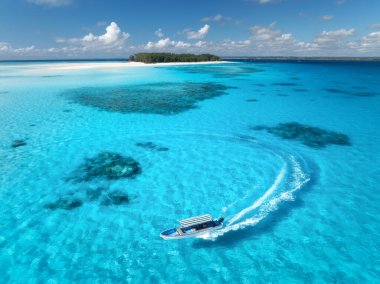 Aerial view of floating boat in transparent azure water on sunny summer day. Mnemba island, Zanzibar. Top view of yacht, sandbank in low tide, clear blue sea, sand, sky with clouds. Motorboat in ocean clipart