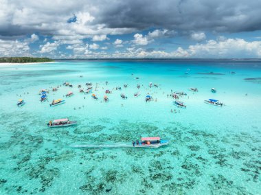 Aerial view of colorful boats in clear azure water in summer. Mnemba island, Zanzibar. Top drone view of sandbank in low tide, blue sea, white sand, swimming people, yachts, sky with clouds. Ocean clipart