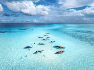 Aerial view of colorful boats in clear azure water in summer. Mnemba island, Zanzibar. Top drone view of sandbank in low tide, blue sea, white sand, swimming people, yachts, sky with clouds. Ocean clipart