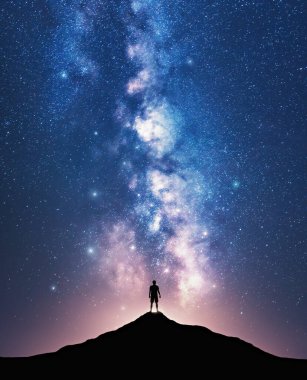 Parlayan Samanyolu ve yıldızlı gecede dağın zirvesinde bir adam. Tepede parlak yıldızlı bir adamın silueti. Galaksi. Samanyolu ile uzay manzarası. Gece manzarası. Seyahat geçmişi. Kavram