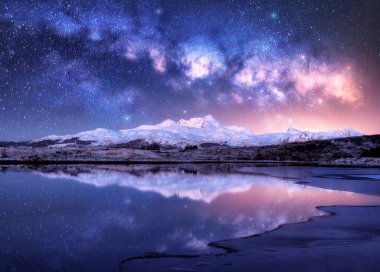 Kış gecesi, karlı dağların ve deniz kıyısının üzerinde parlak Samanyolu. Karlı kayalıklı manzara, yıldızlı gökyüzü, suda yansıma, fiyort. Lofoten Adaları, Norveç. Boşluk. Parlayan Samanyolu ve yıldızlar