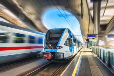 Yüksek hızlı mavi yolcu treni gün batımında tren istasyonunda hareket ediyor. Tren istasyonu. Bulanık hareket etkisine sahip modern demiryolu taşımacılığı konsepti. Demiryolu. Reklam. Demiryolu taşımacılığı